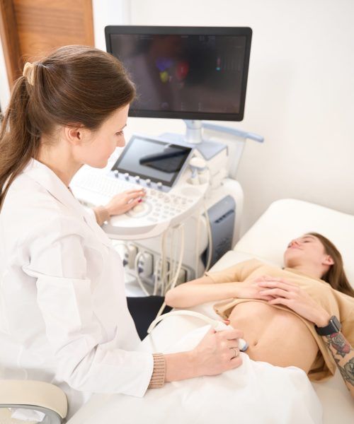High angle view of gynecologist doing ultrasound scan of pregnant woman belly